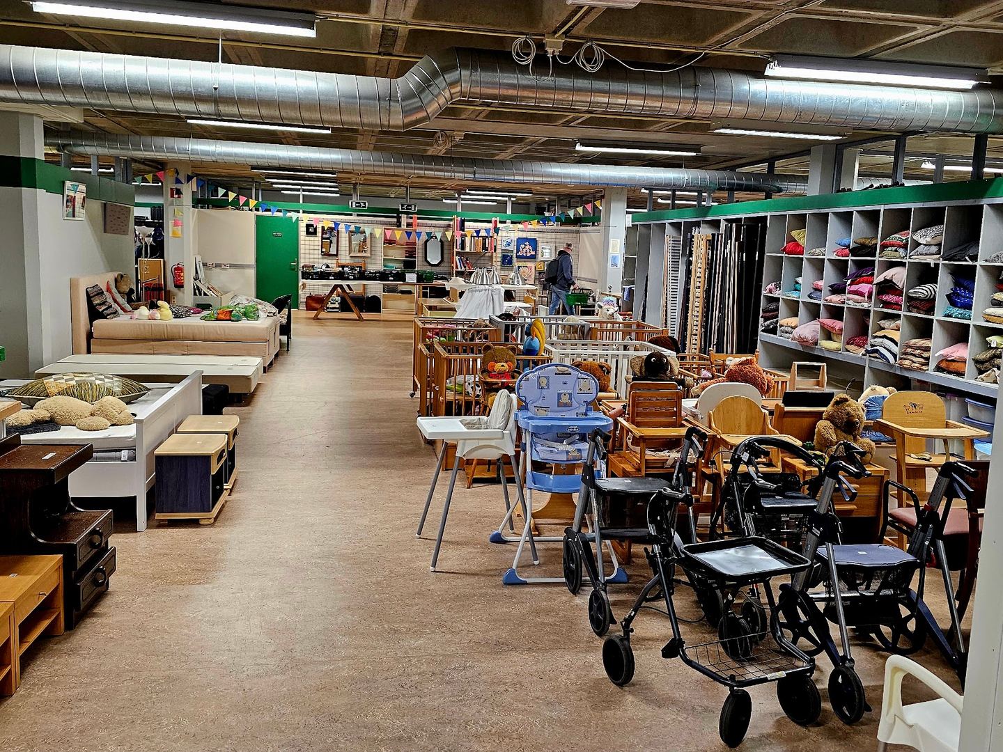 Lange winkelgang in De Pelgrimshoeve met meubels, kinderstoelen en schappen vol textiel