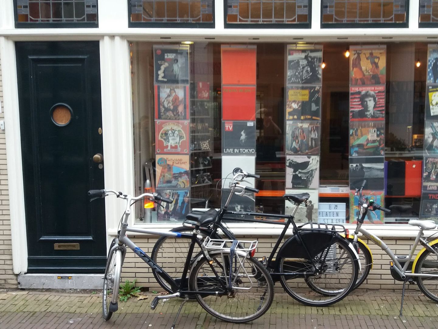 Gevel van De Platenslager met platenhoezen in de etalage en fietsen voor de deur