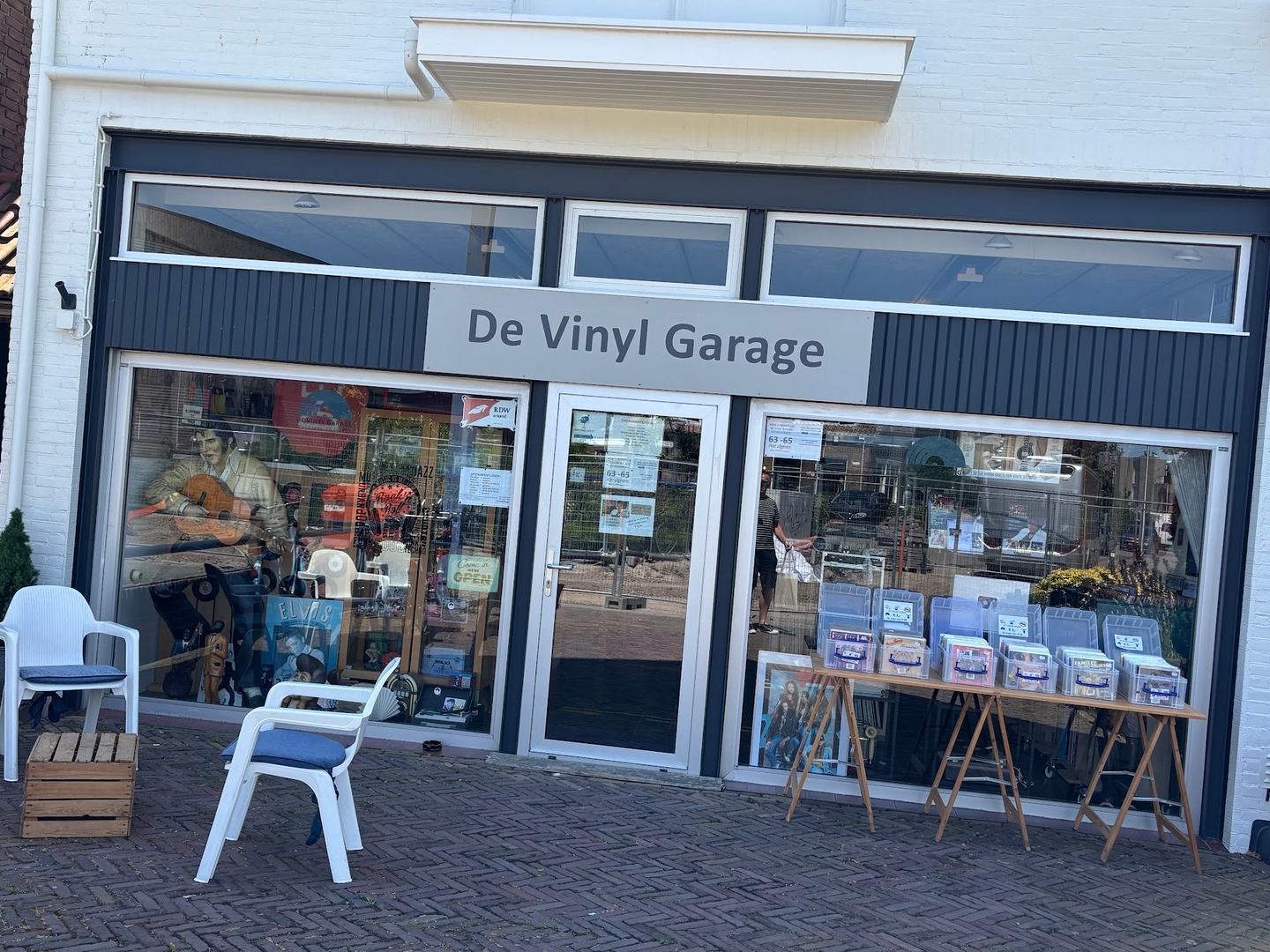 Gevel van De Vinyl Garage met etalages en platenbakken op een tafel voor de deur