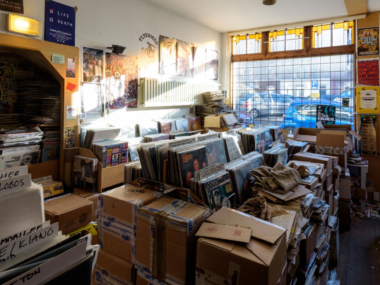 Interieur van Distortion Records met bakken vol platen en stapels dozen