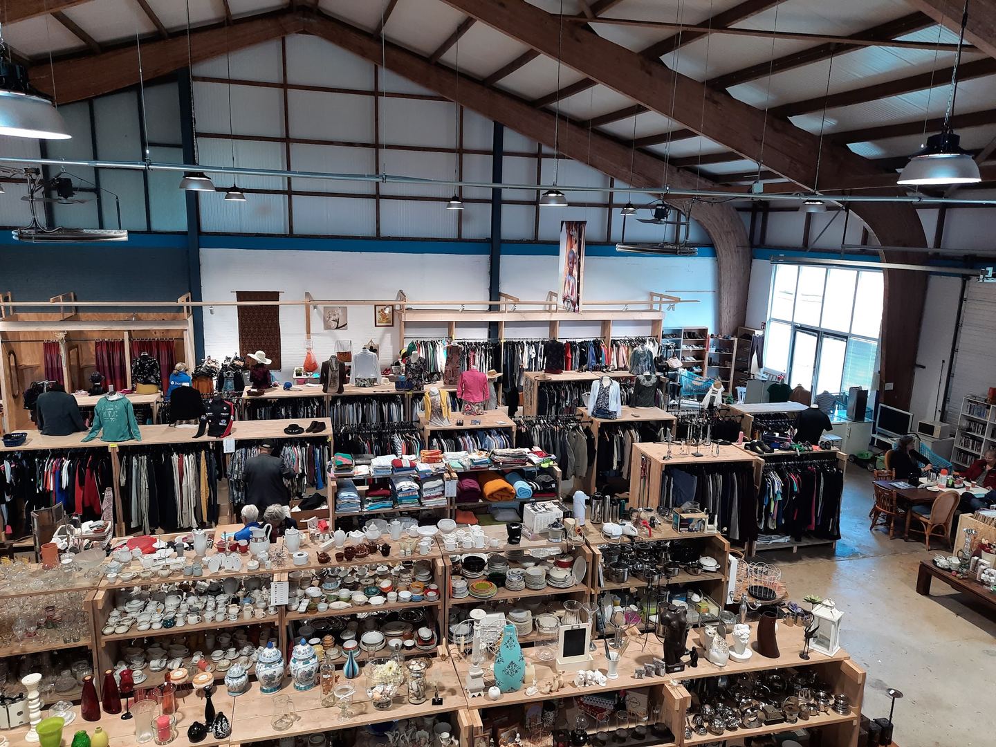 Winkelhal van Dorcas Winkel Appingedam met tafels vol servies en rekken kleding