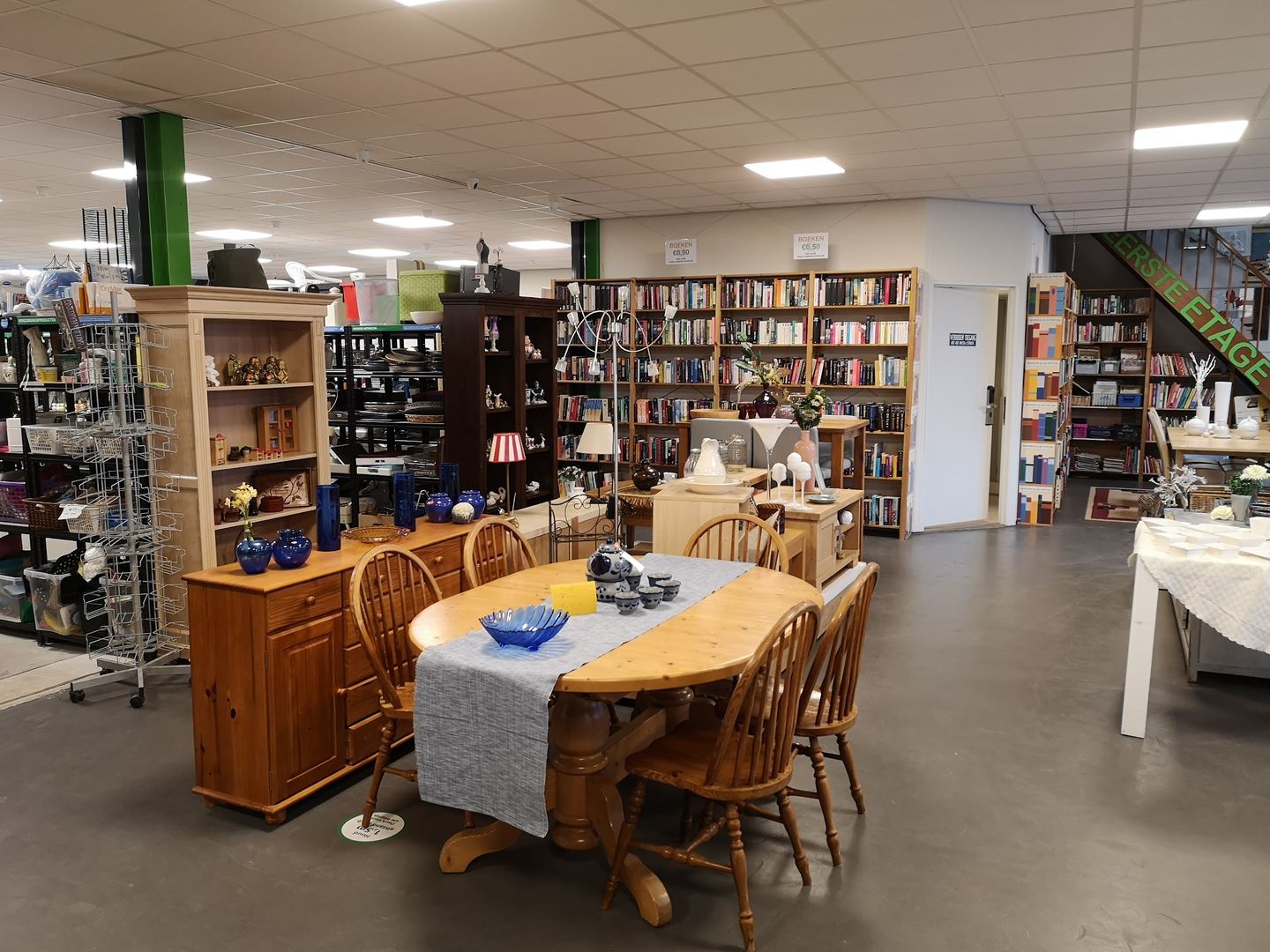 Interieur van Dromehof met een houten eettafel, kasten met servies en rekken vol boeken