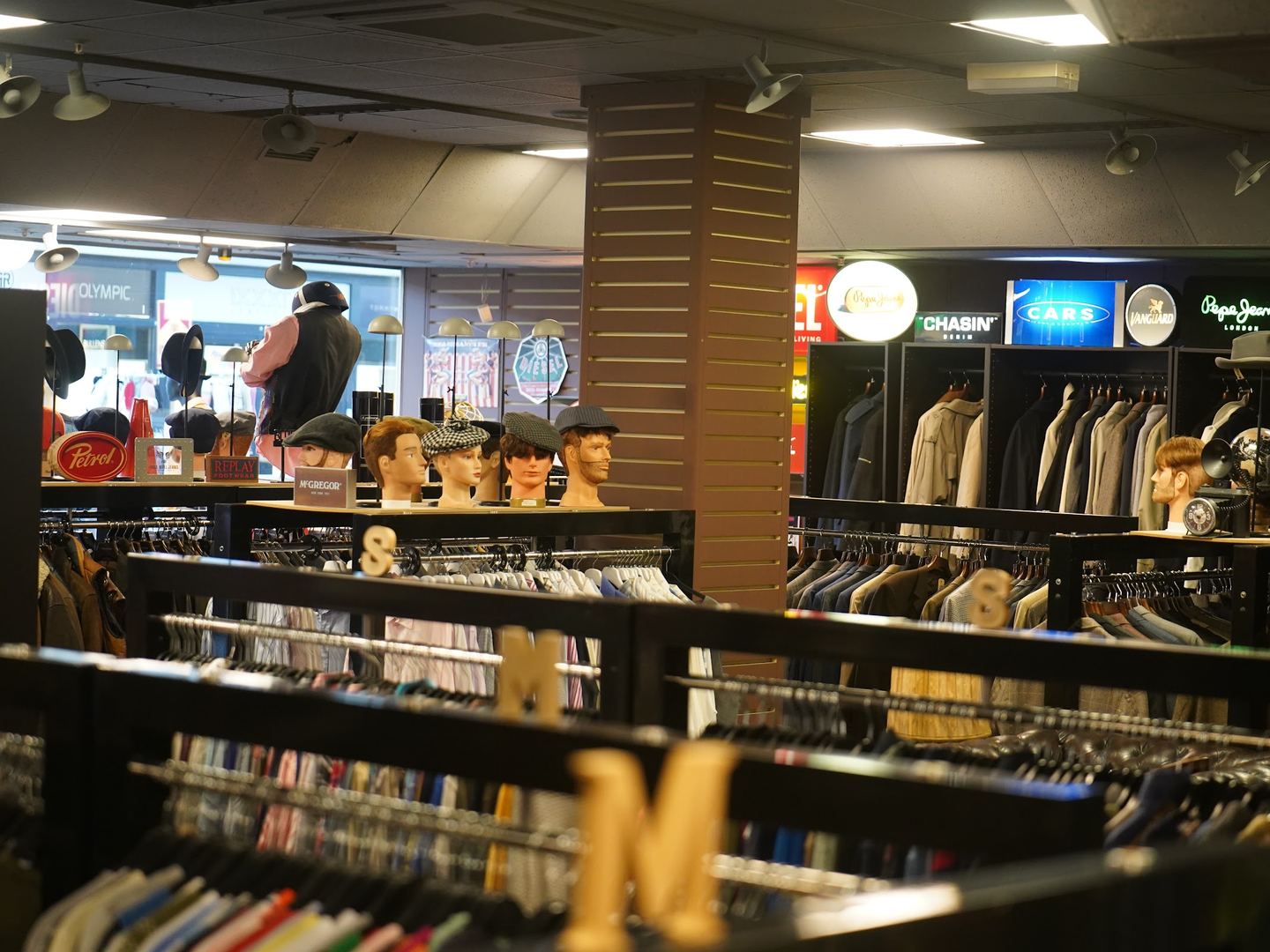 Rekken met tweedehands herenkleding, pakken en hoeden in de winkel van EcoGents