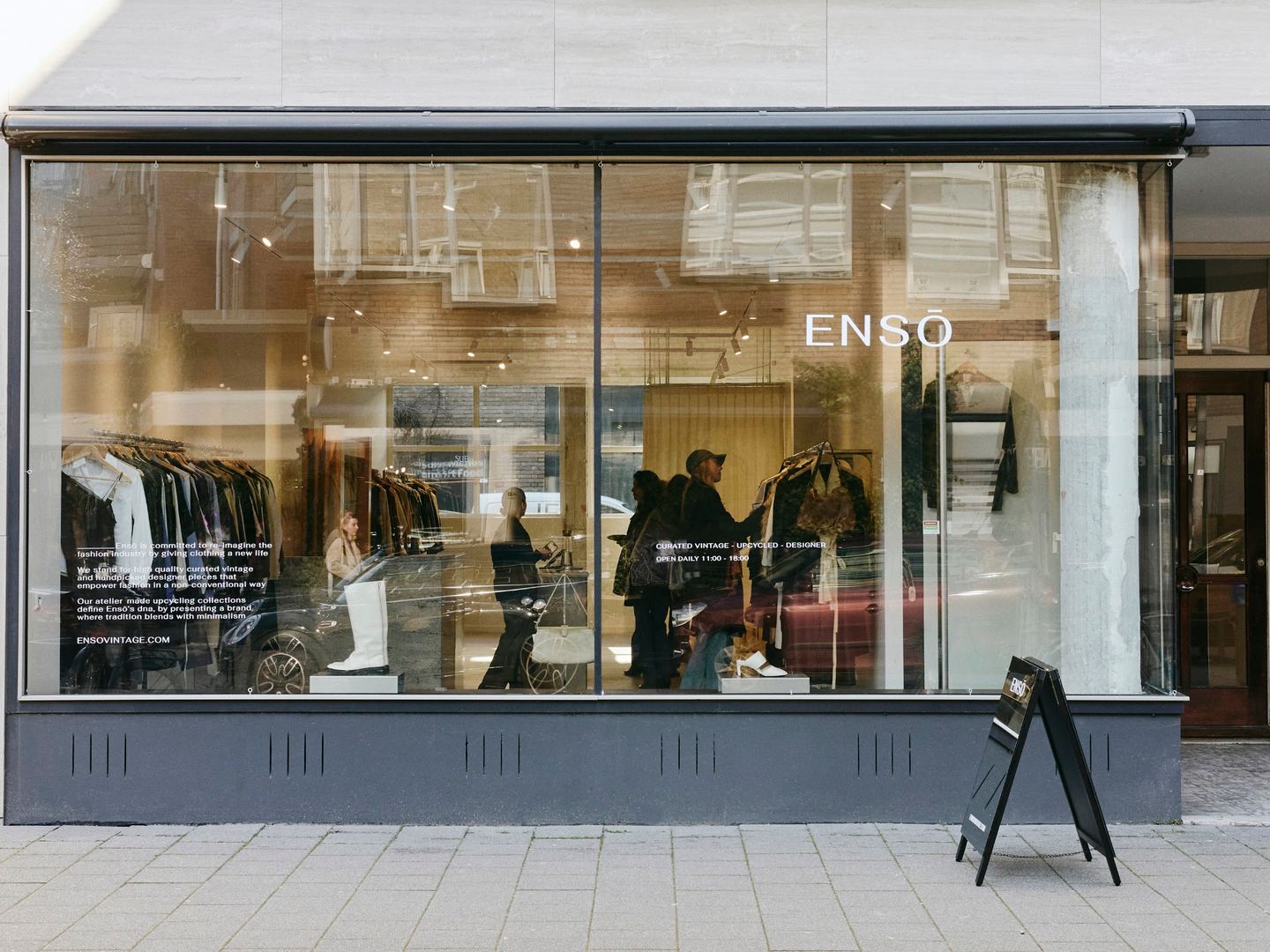 Etalage van ENSŌ Vintage Rotterdam met rekken vintage kleding achter het glas