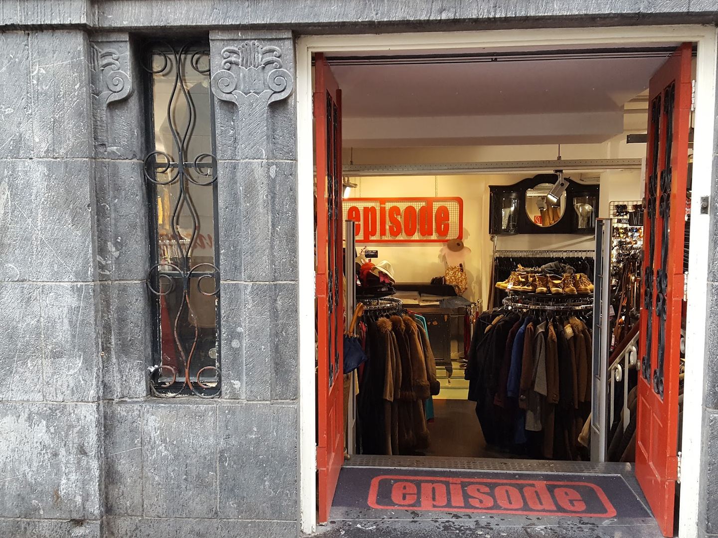 Ingang van Episode in een stenen gevel met zicht op rekken kleding