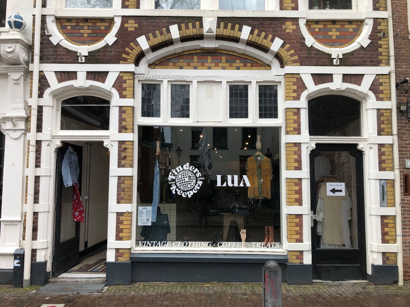 Geel-rode bakstenen gevel met het logo van Finders Keepers op de etalage, vintage kleding en twee open deuren