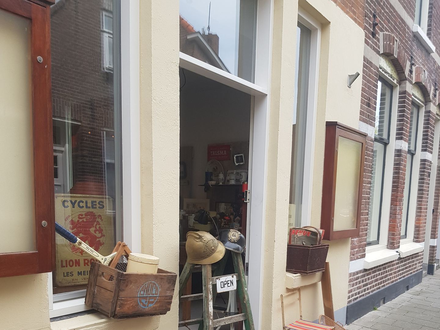 Ingang van Framantique met een oud trapje, antieke helmen en een kistje curiosa voor de deur