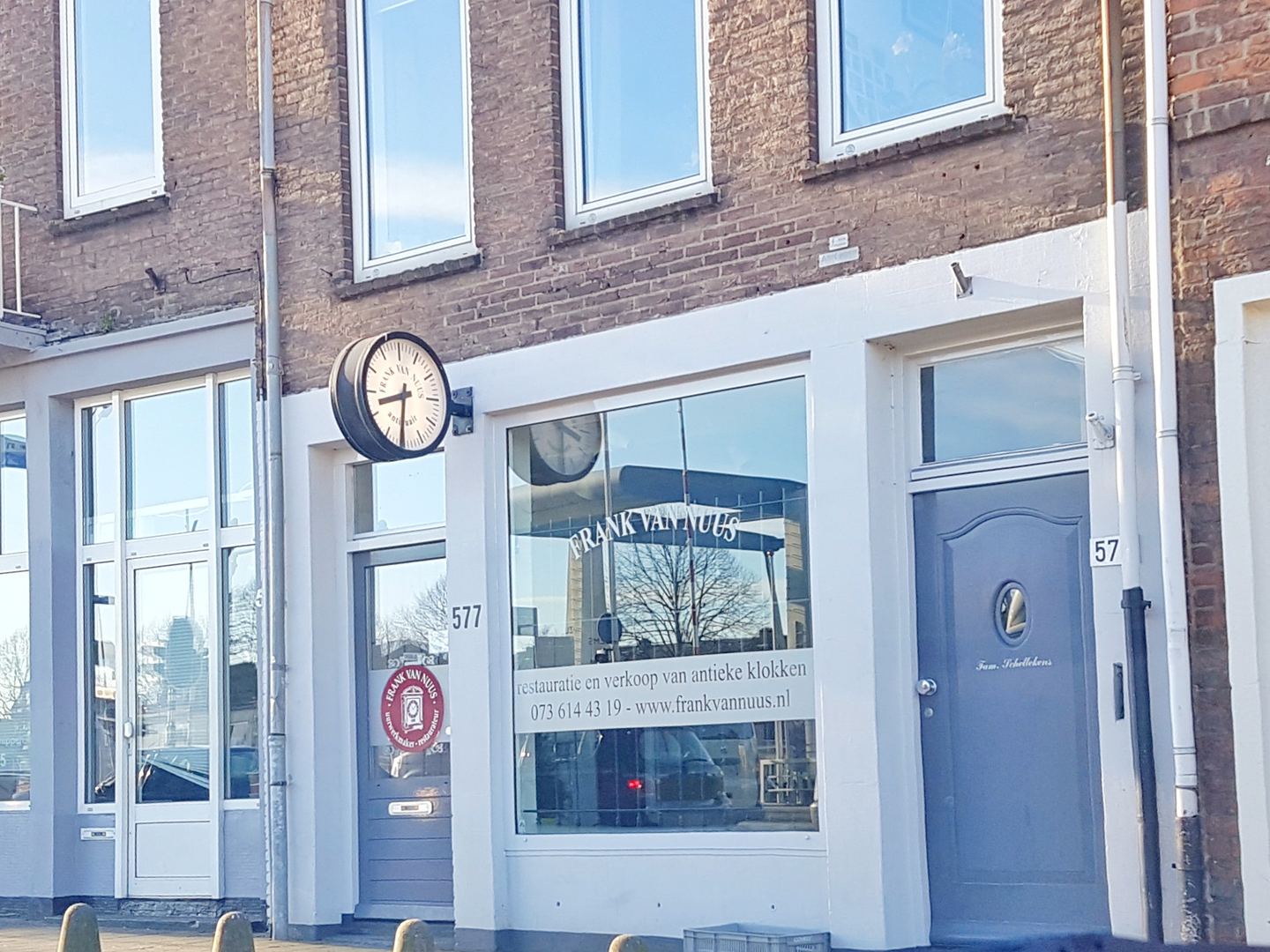 Winkelpui van Frank van Nuus met een ronde klok aan de gevel en de naam op de etalageruit