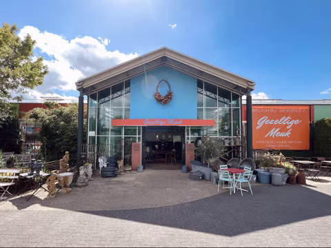 Buitenaanzicht van de brocantehal met blauwe gevel en een oranje winkelbord