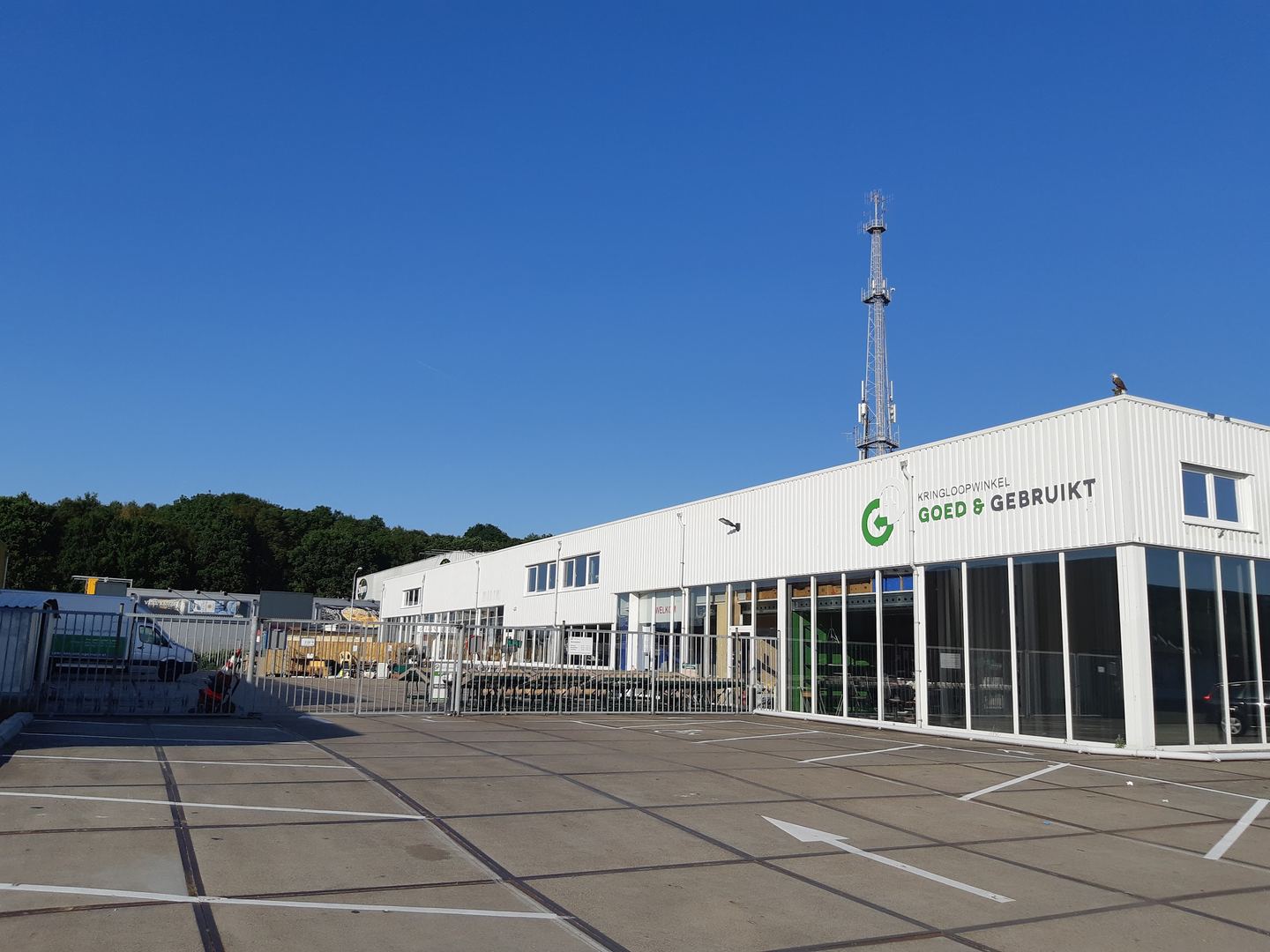 Gevel van Kringloopwinkel Goed & Gebruikt met het parkeerterrein ervoor