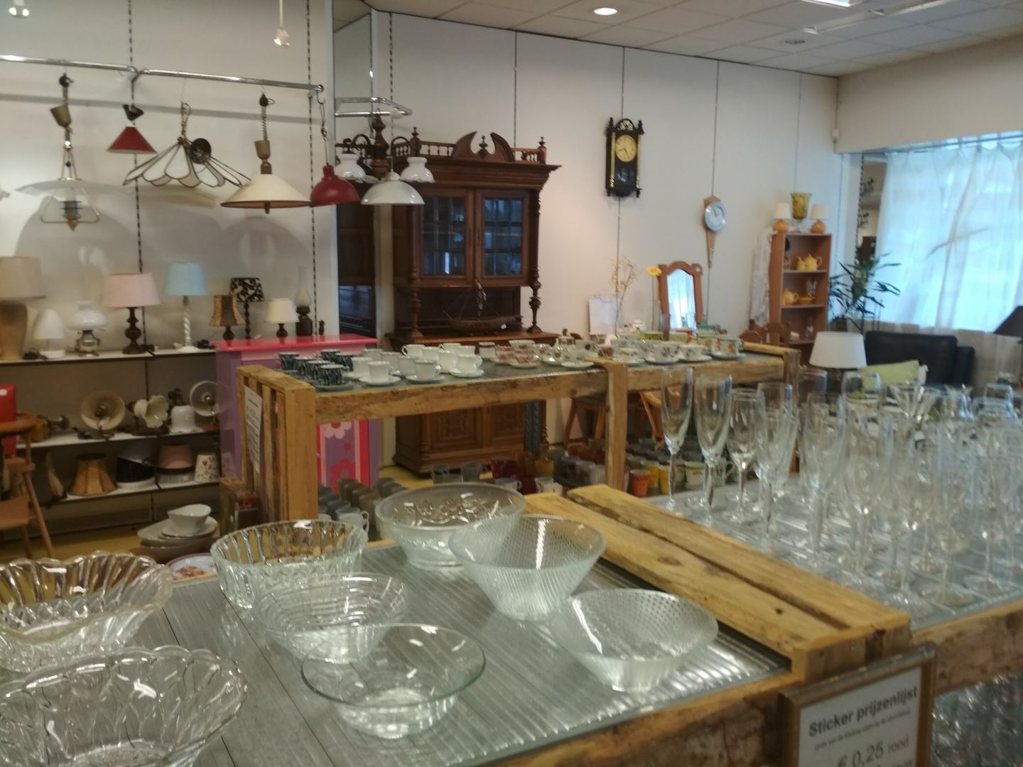 Glaswerk, lampen en een oude kast in GoudGoed Kollum