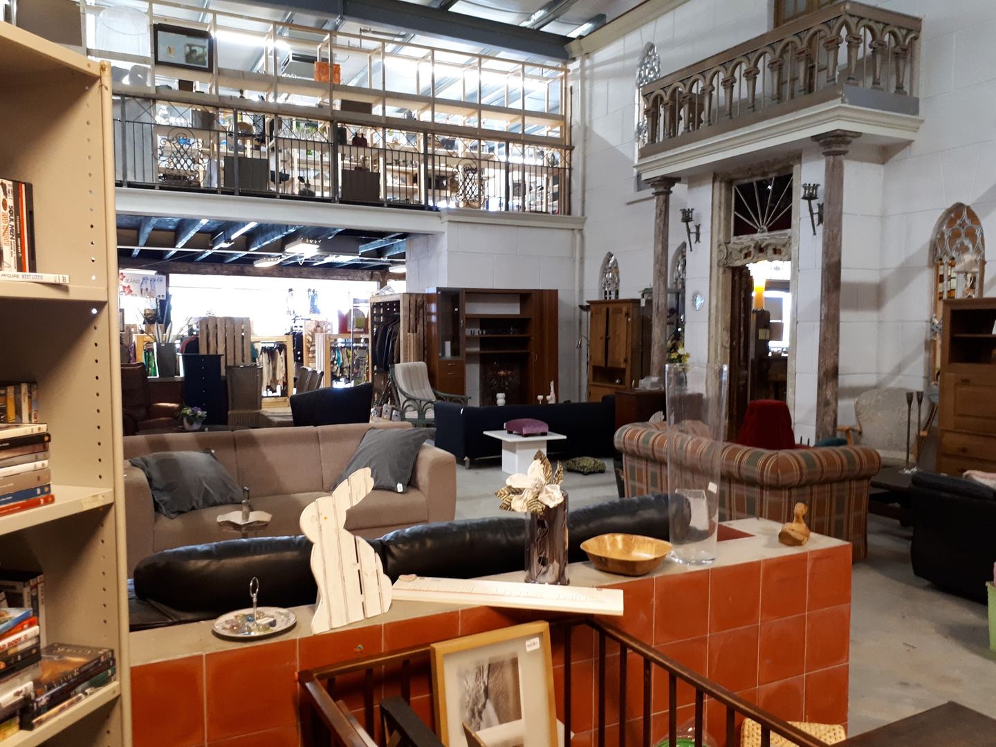 Interieur van GoudGoed Winsum met meubels, kasten en een vide met balustrade