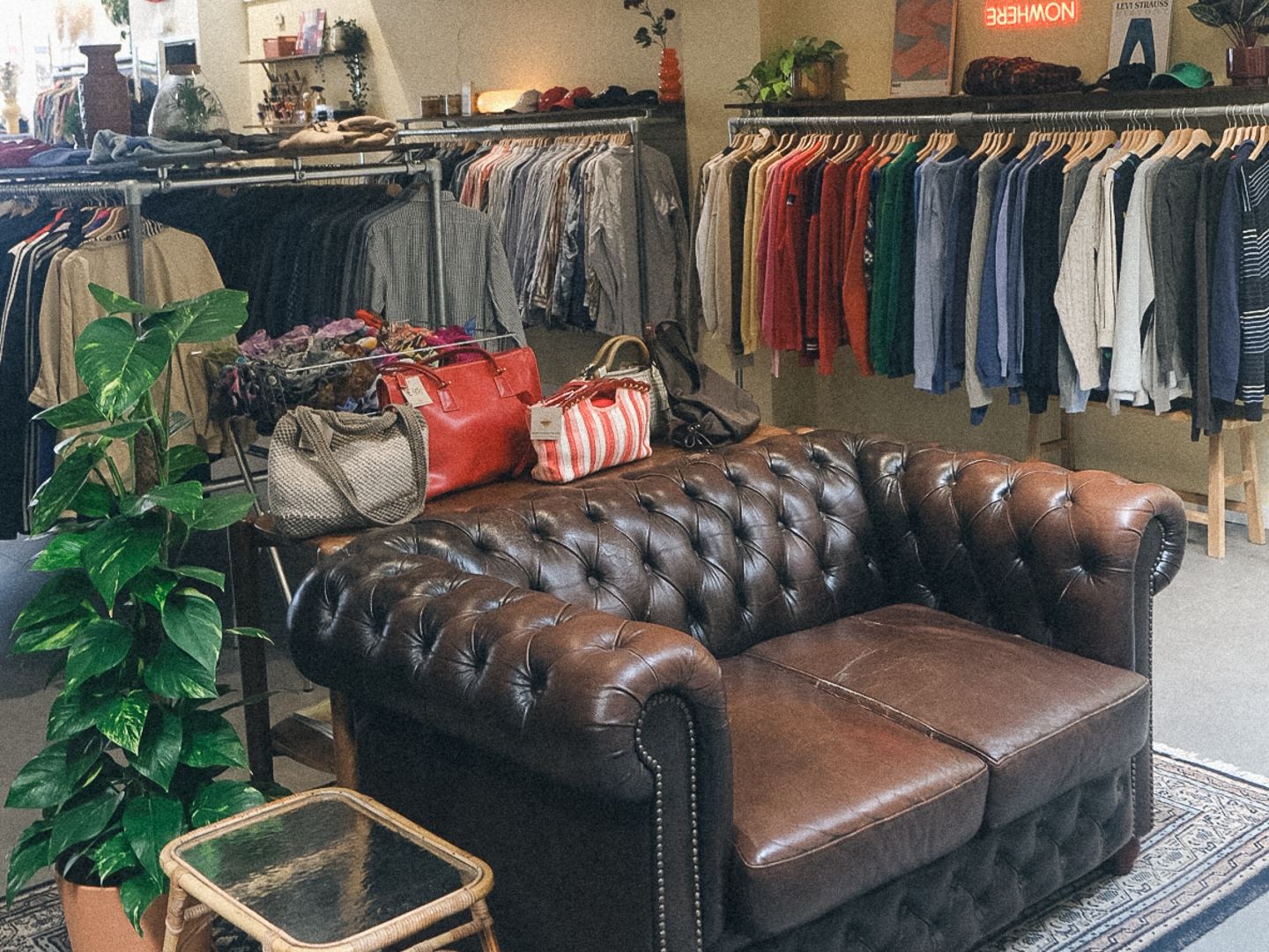 Rekken met vintage kleding en een leren chesterfield in Groovy Anton