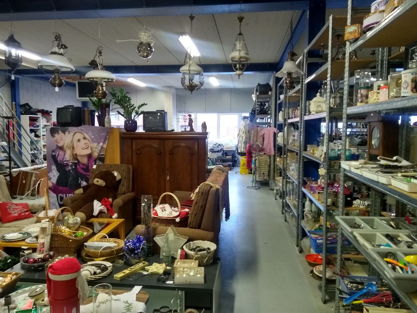 Interieur van Kringloopwinkel Habbekrats met stellingkasten vol servies, hanglampen, kasten en knuffels