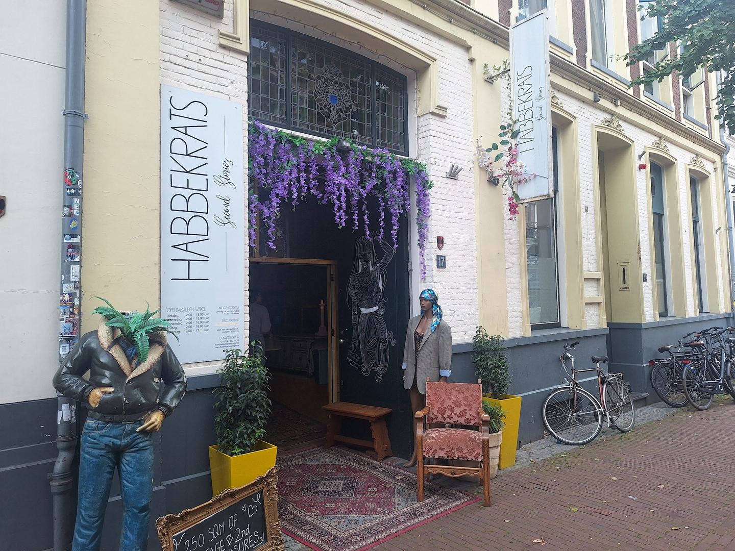 Gevel van Habbekrats met naambord, bloemenslinger boven de ingang en een etalagepop