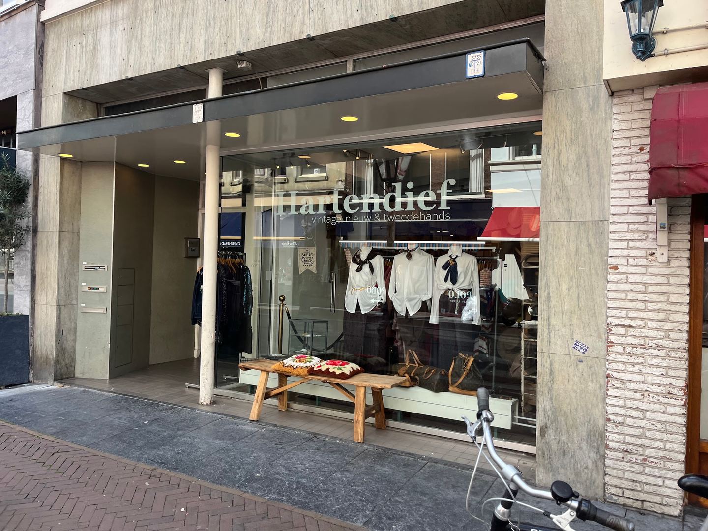 Gevel van Hartendief met de naam op de etalageruit en rekken met kleding achter het glas
