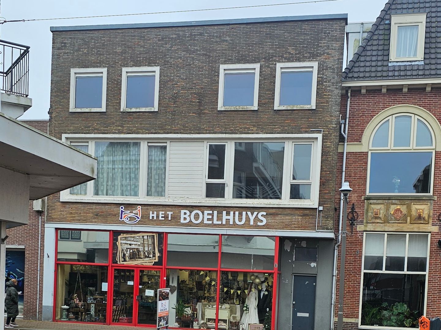 Winkelpui van Het Boelhuys met rode kozijnen en naambord boven de etalage