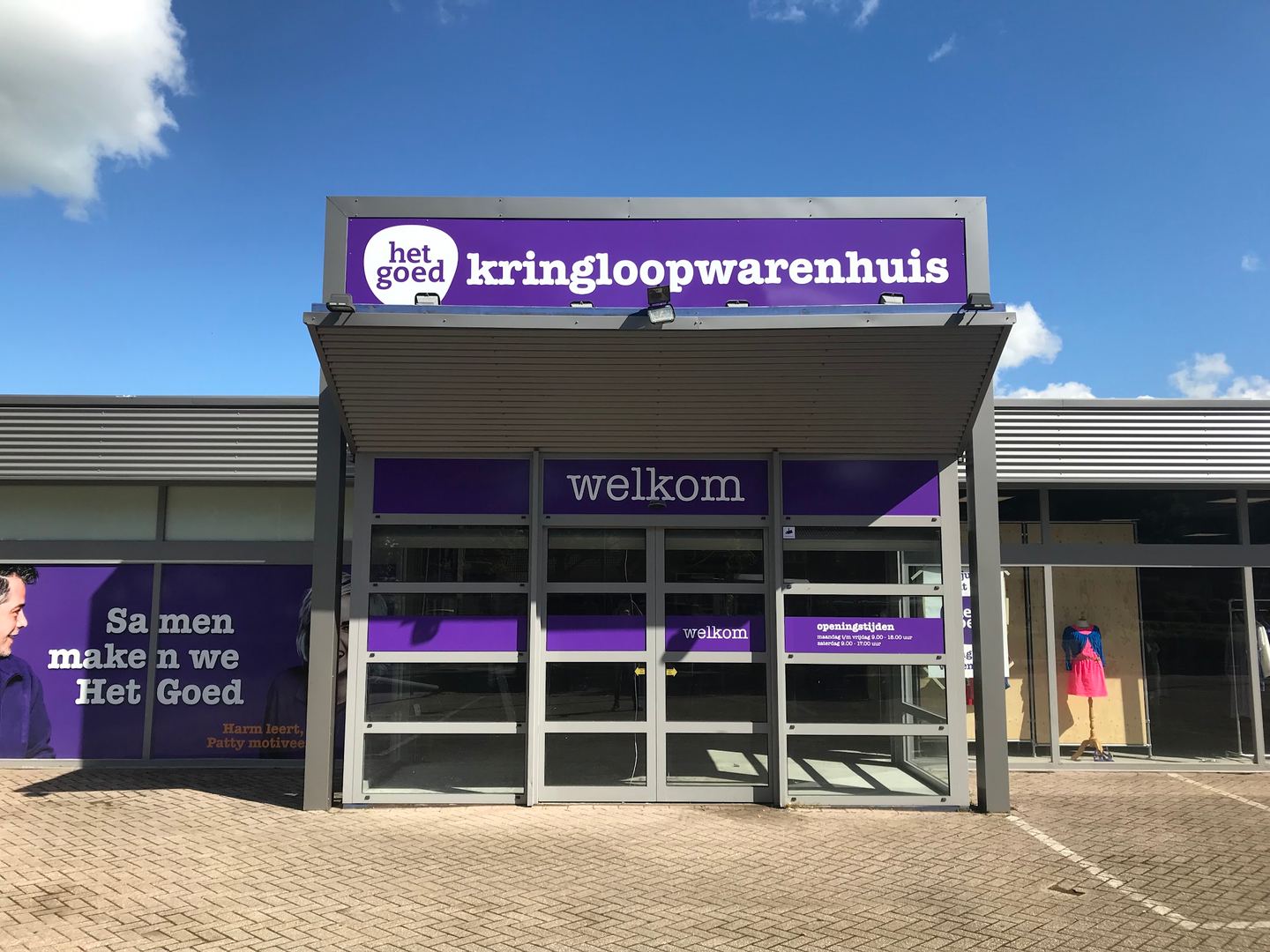 Ingang van Kringloopwarenhuis Het Goed Sittard met paarse luifel en welkomstbord
