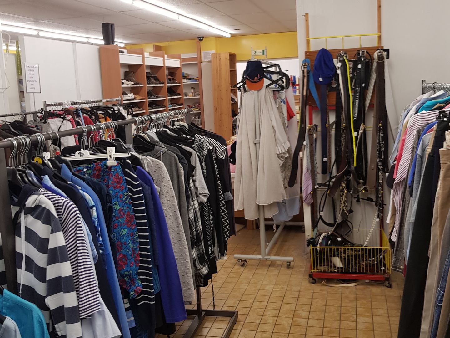 Interieur van Kringloopwinkel Het Goede Doel met rekken vol tweedehands kleding en kasten met schoenen
