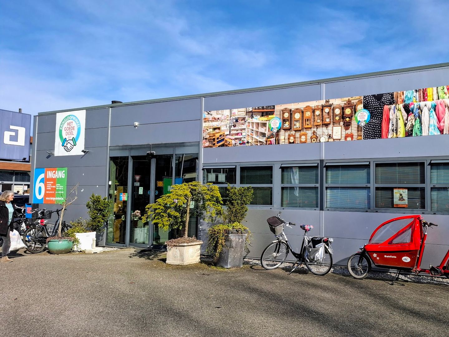 Gevel van Kringloopwinkel Het Goede Doel met ingang, logo en fietsen voor de deur