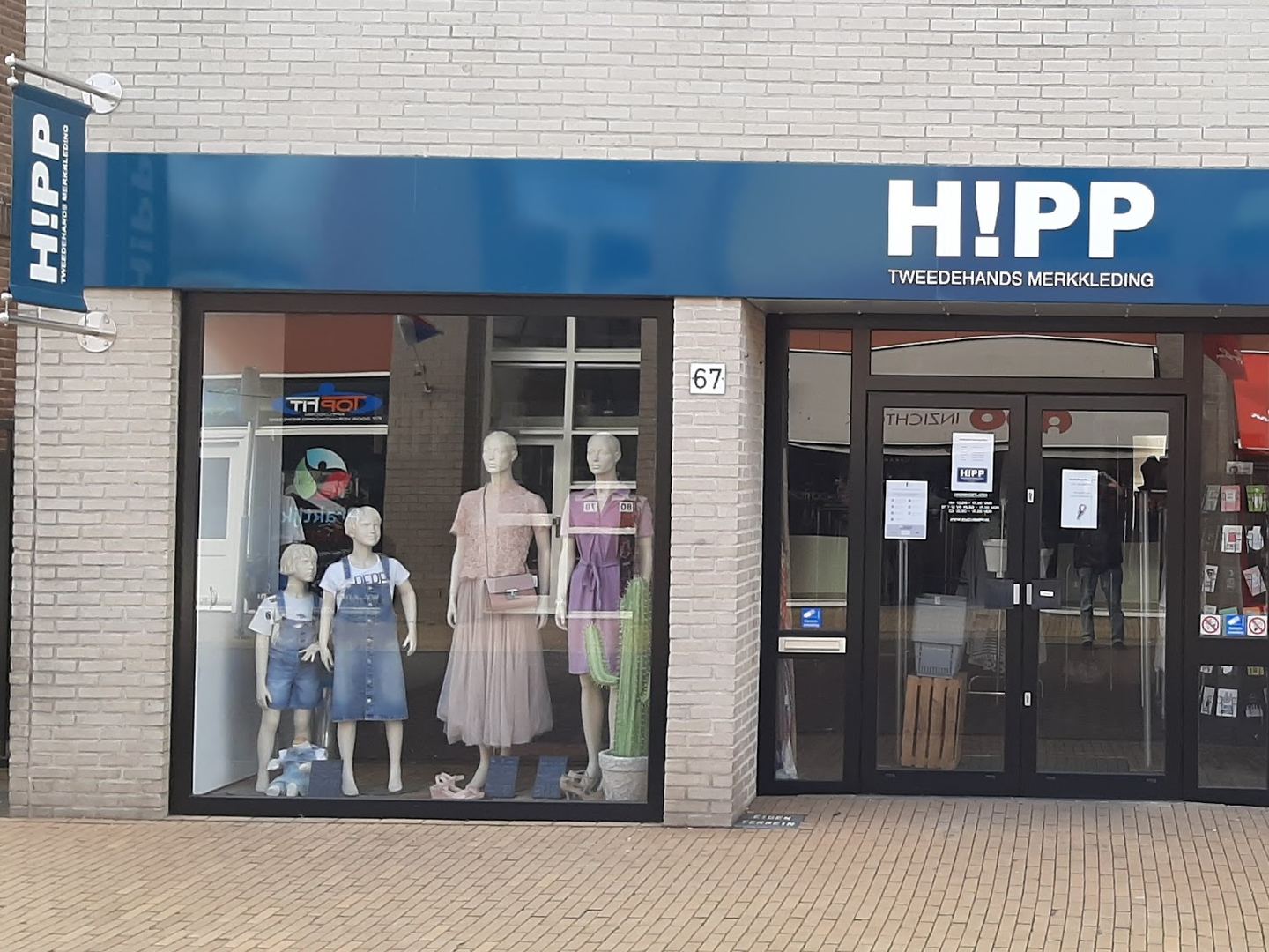 Winkelpui van HIPP Apeldoorn met kleding in de etalage en blauw naambord