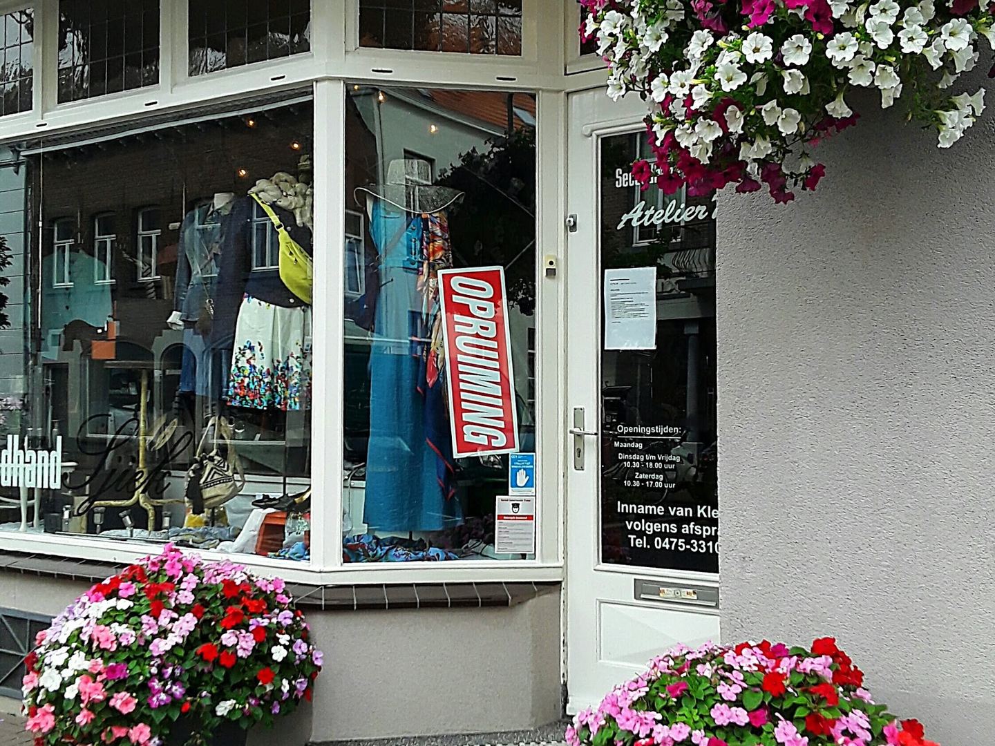 Winkelpui van KAAT Fabrics met etalage vol kleding en hangende bloembakken