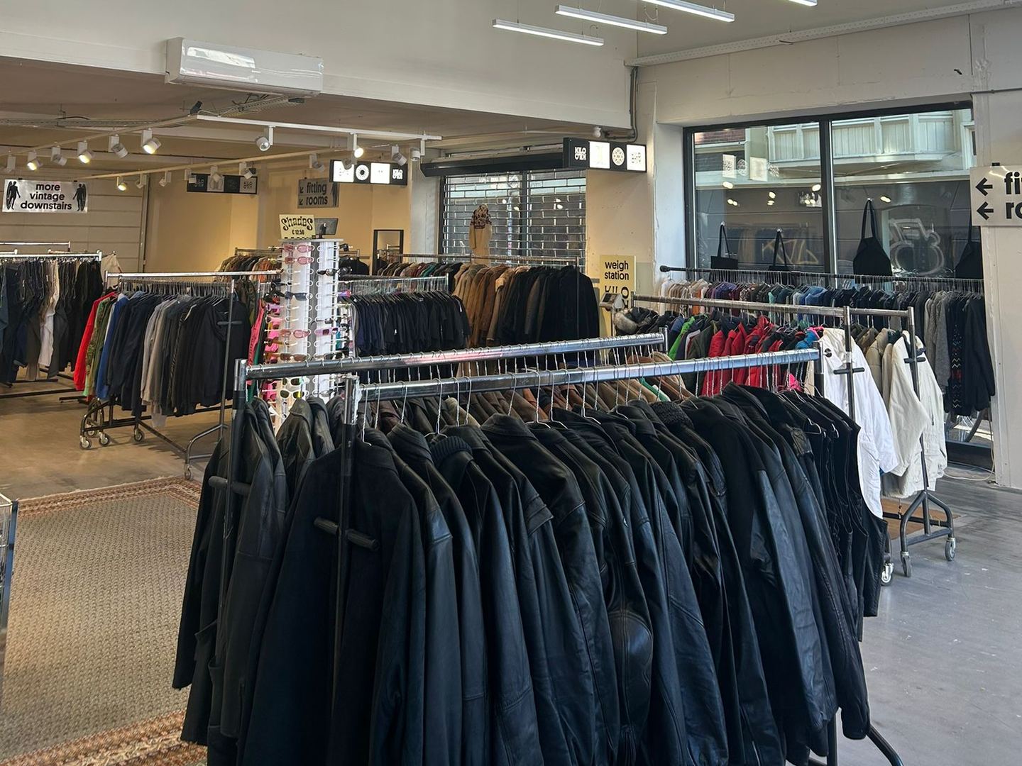 Ruime winkelvloer van Kilo Kilo met een rek vol leren jassen en rijen kledingrekken onder tl-licht