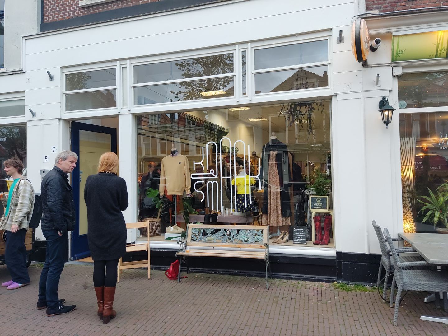 Witte winkelpui van Knaak & Smaak met logo op de etalage en kleding aan rekken