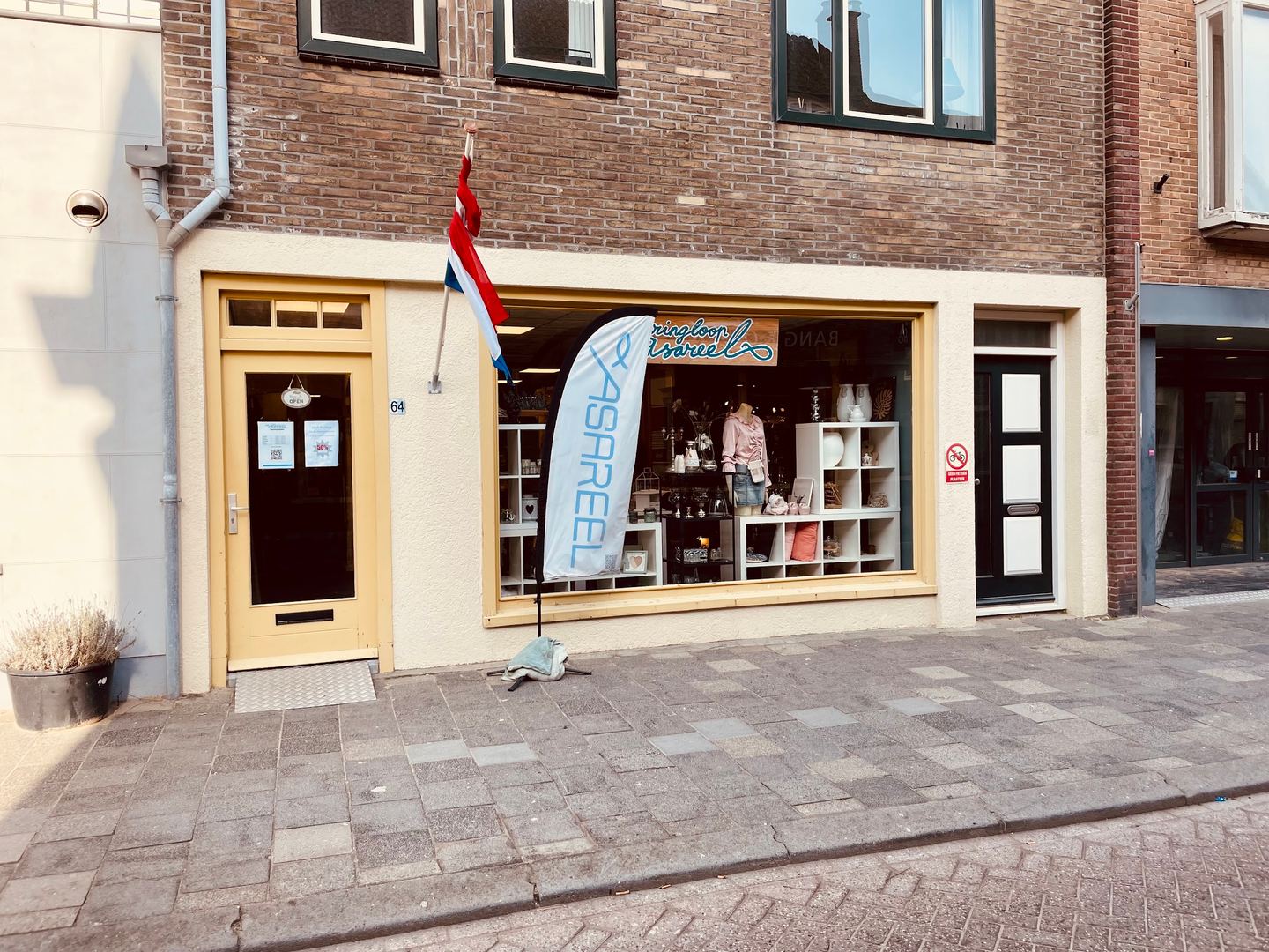 Gevel van Kringloop Asareel met etalage en een vlag met de naam van de winkel