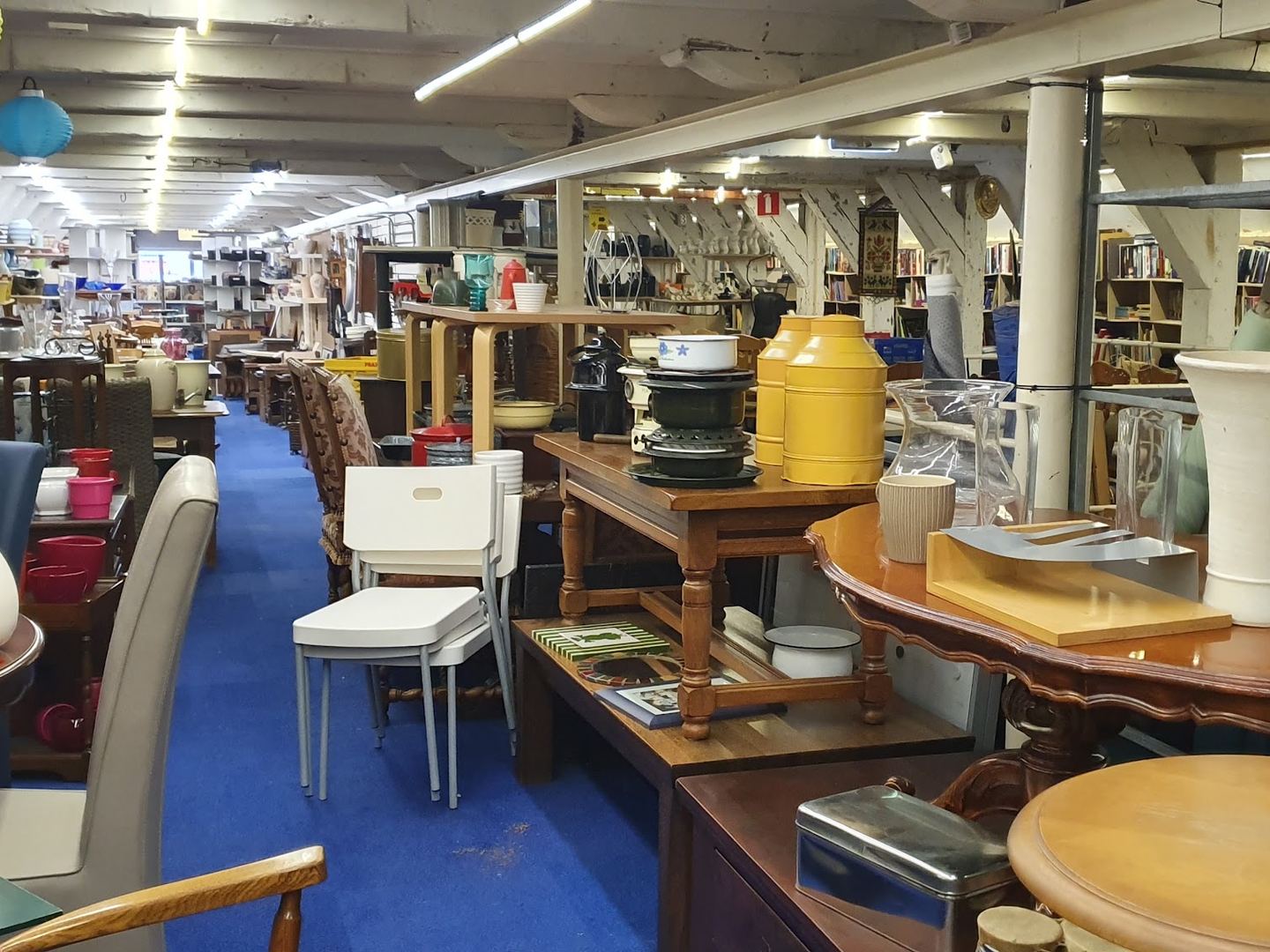 Lange winkelvloer van Kringloop Boeldag met tafels, stoelen, vazen en volle stellingen