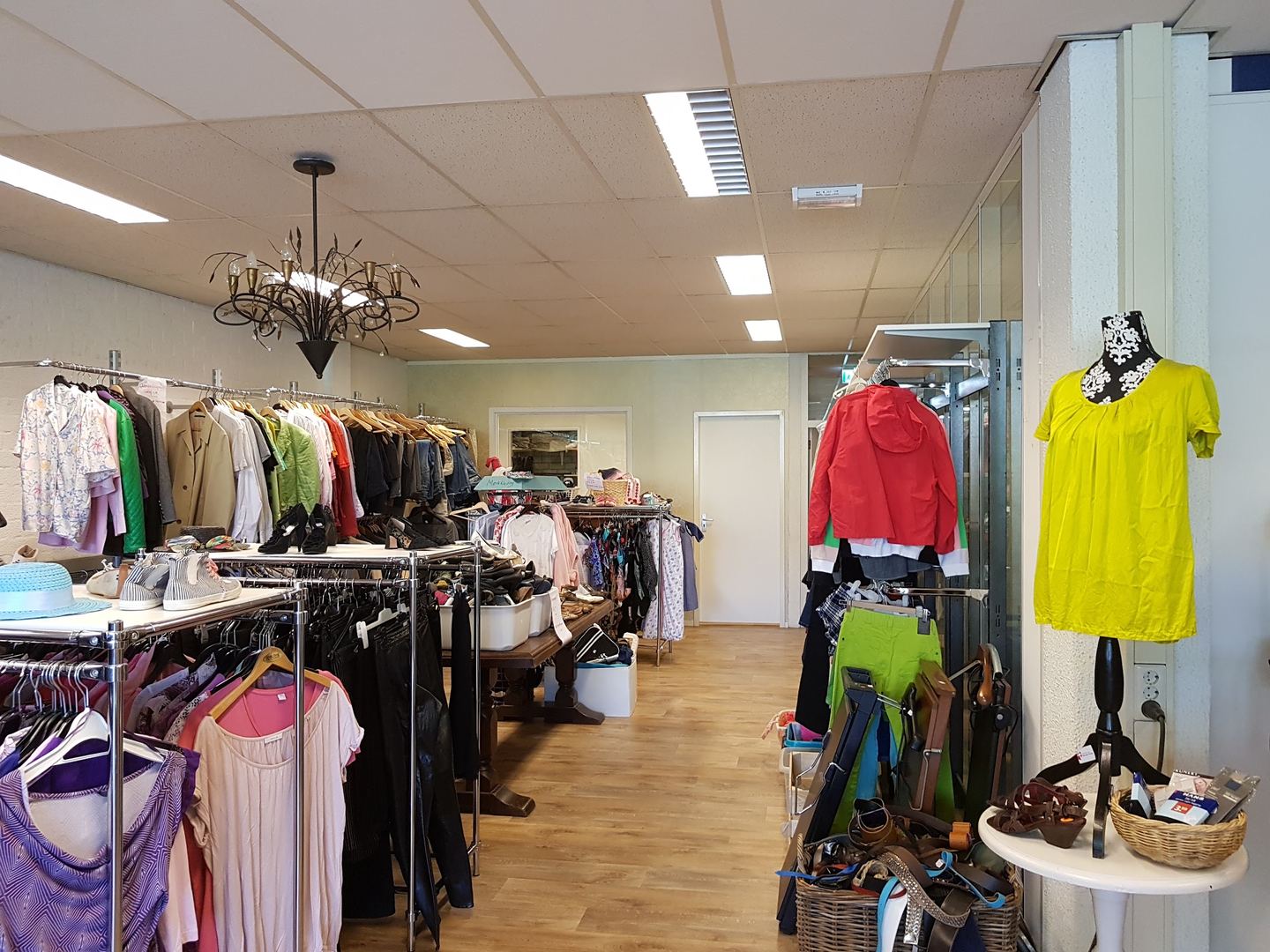 Rekken met tweedehands kleding en een kroonluchter in Kringloop Bonnefooi
