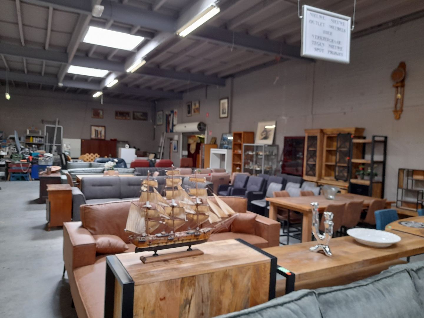 Interieur van Kringloop De Cirkel met leren banken, eettafels en kasten in een grote showroom