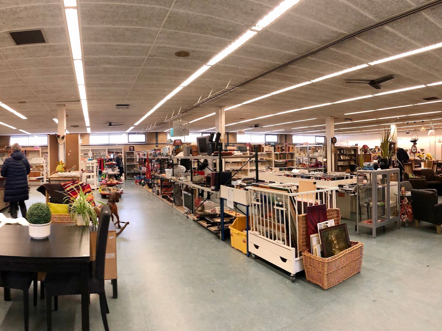Winkelvloer van Kringloop Nieuwe Vorm met meubels, kasten en huisraad onder lange lichtbanen
