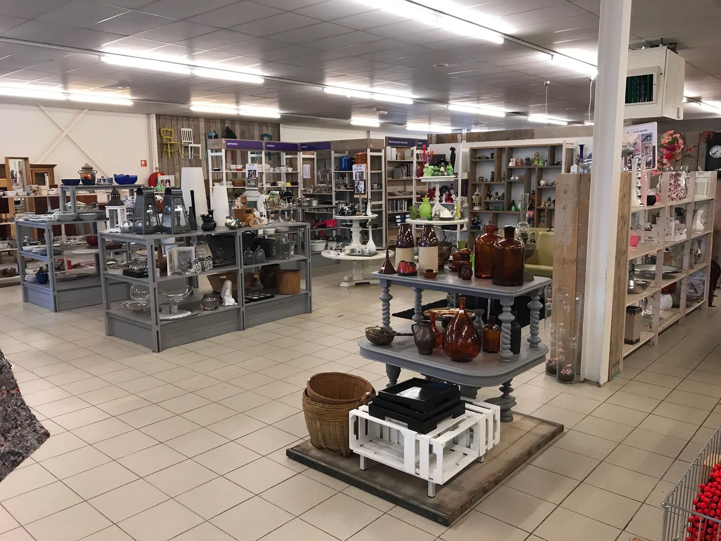 Winkelvloer van Kringloopwarenhuis Het Goed Assen met schappen vol servies, glaswerk en woonaccessoires