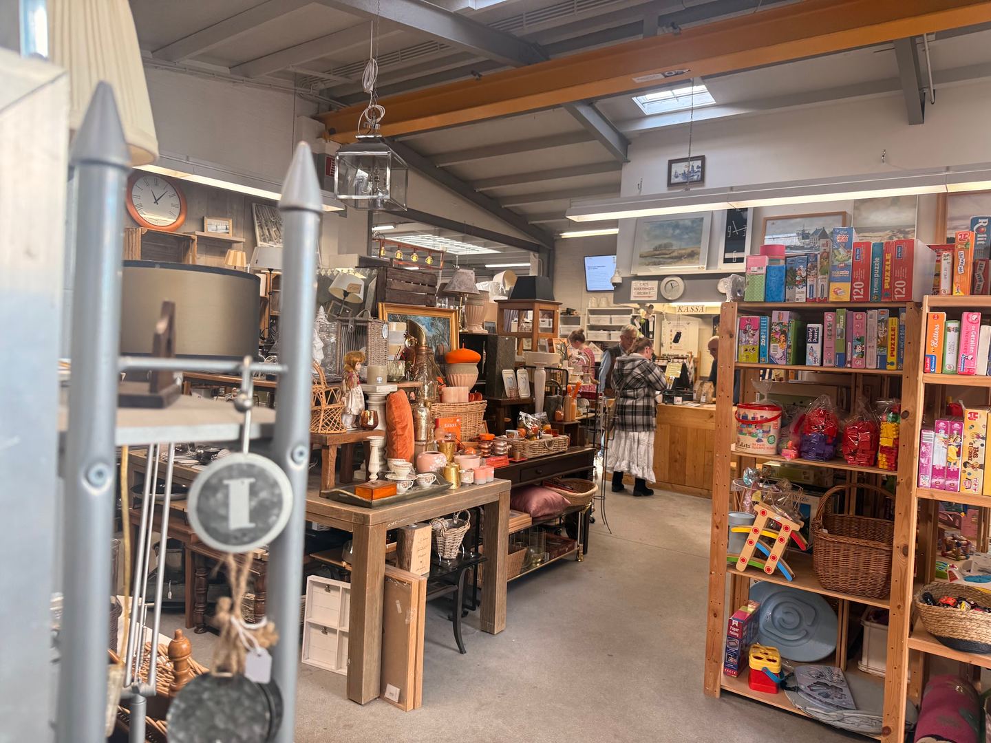 Interieur van De Loop met tafels vol servies en woonaccessoires, een wandklok en kasten met spellen