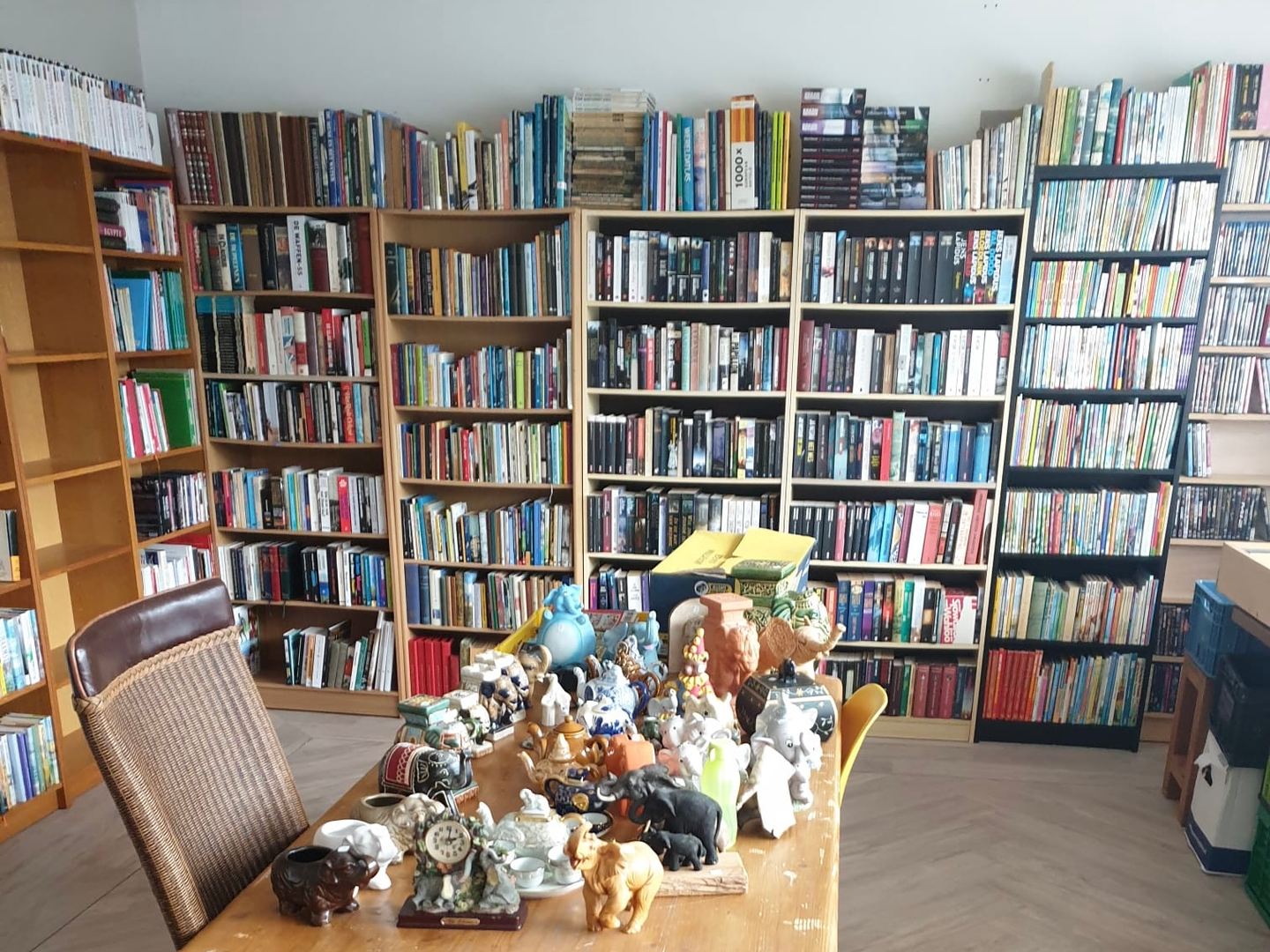Boekenkasten vol boeken en een tafel met beeldjes in Kringloopwinkel De Oude Bakkerij