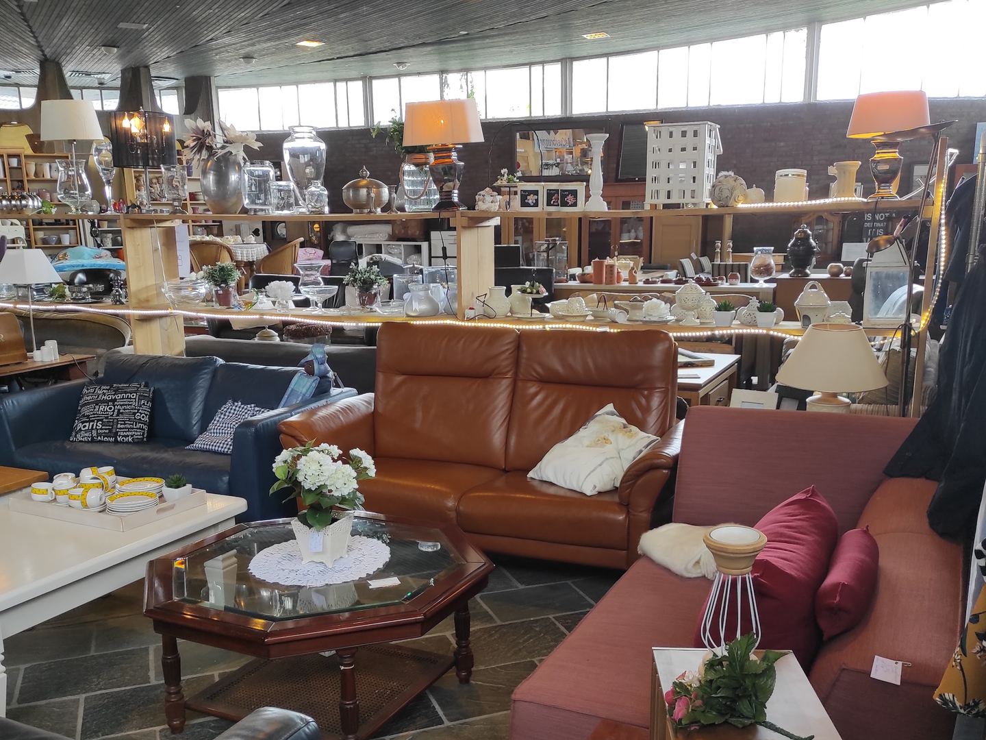 Interieur van Kringloopwinkel De Overbrugging met banken, salontafels en lampen