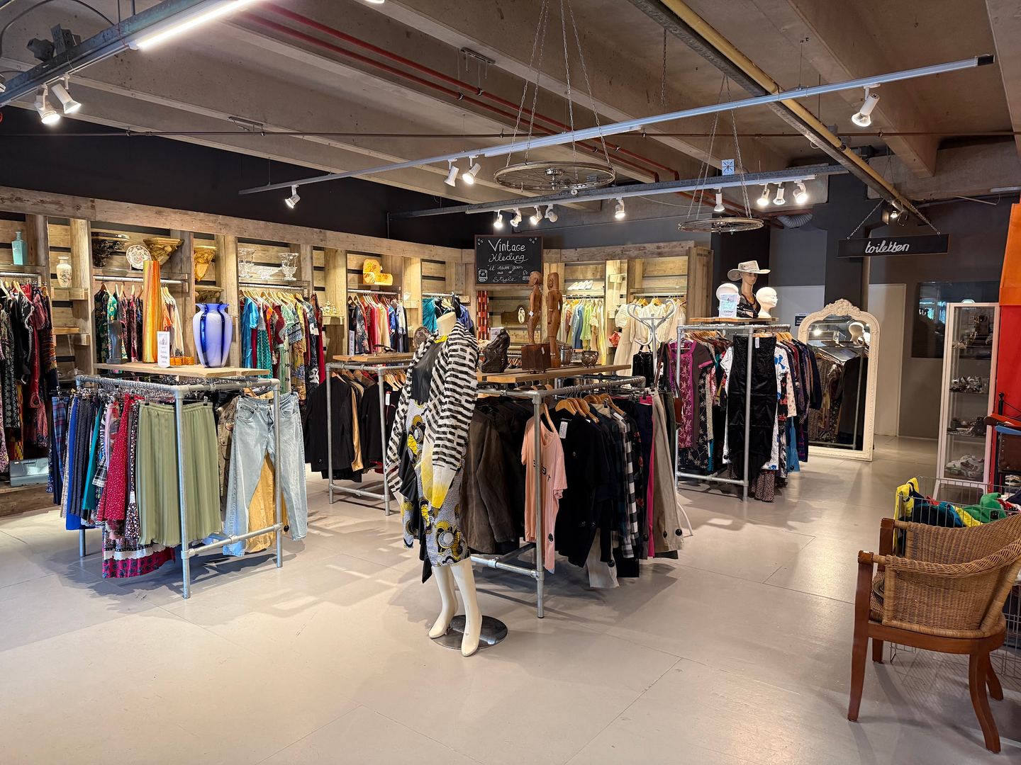Kledingafdeling van Kringloopwinkel De WAAR met rekken tweedehands kleding en paspoppen