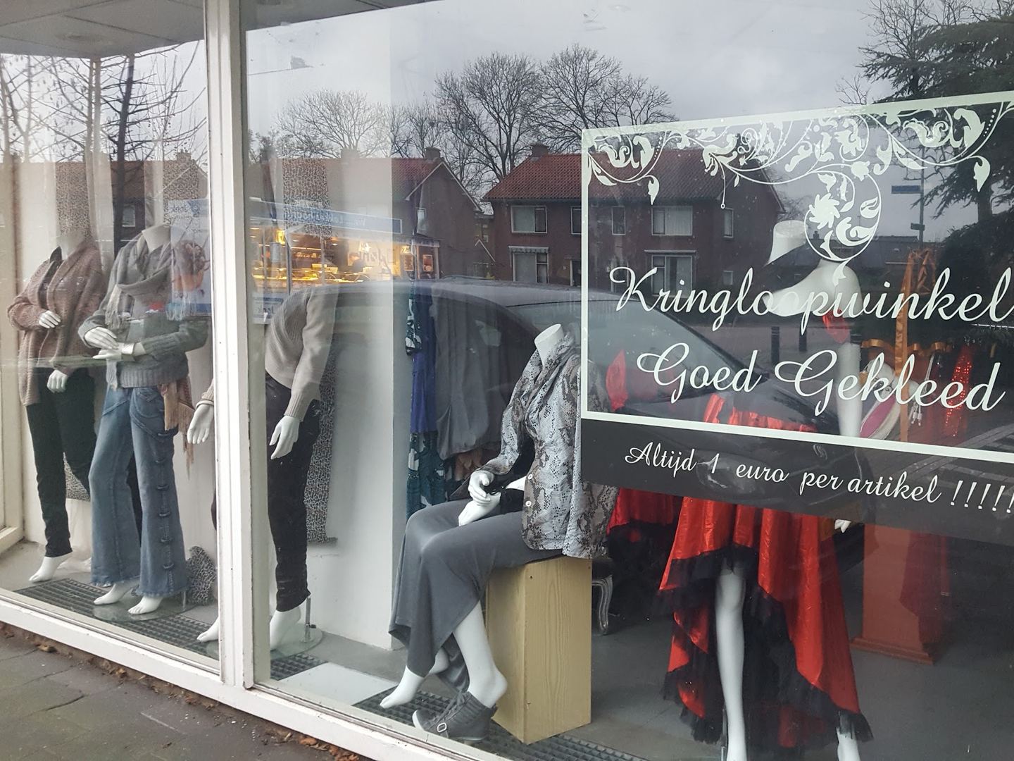 Etalage van Kringloopwinkel Goed Gekleed met mannequins en de winkelnaam op het raam