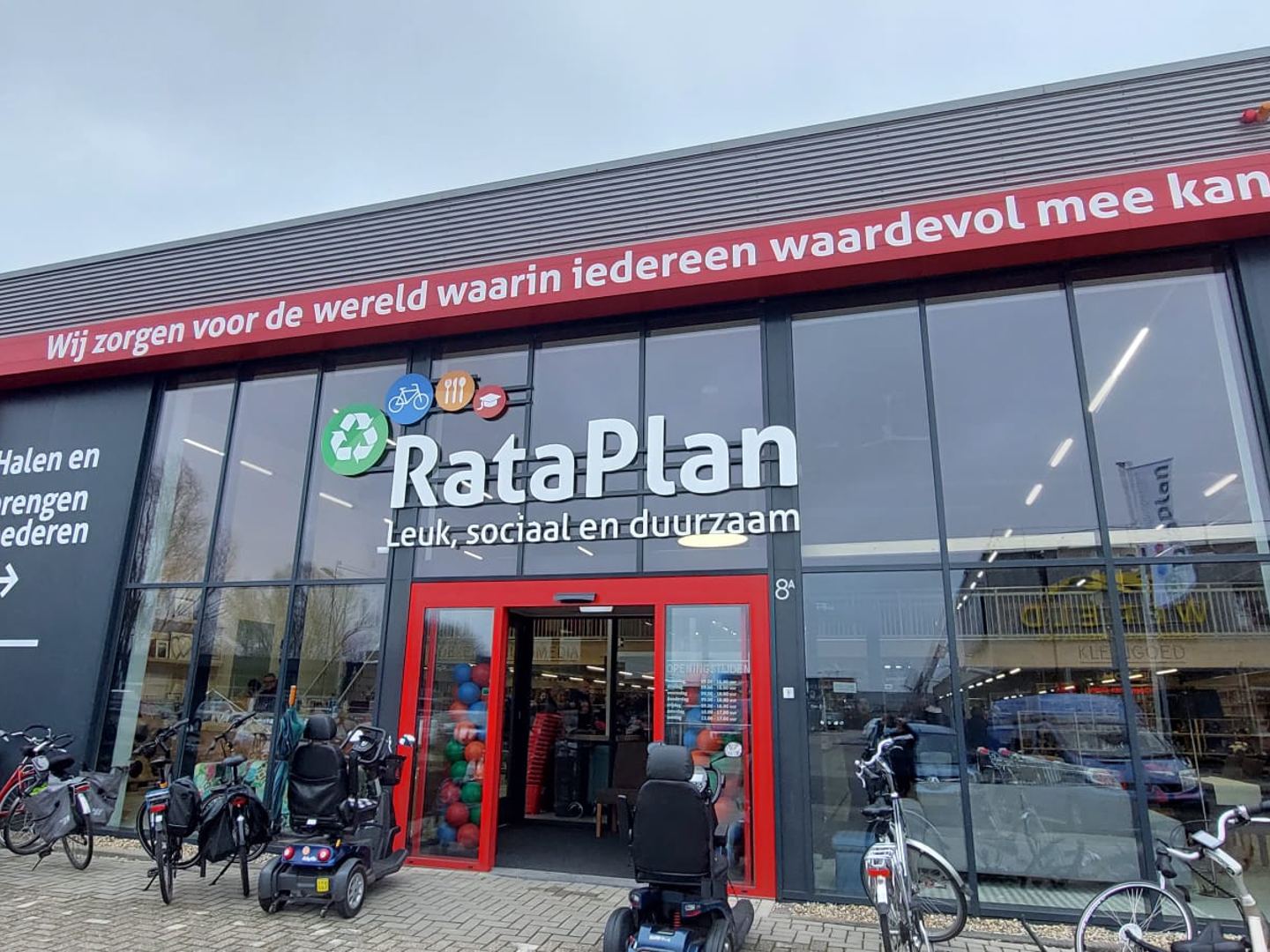 Gevel van Kringloopwinkel RataPlan Arnhem met rode ingang en naambord
