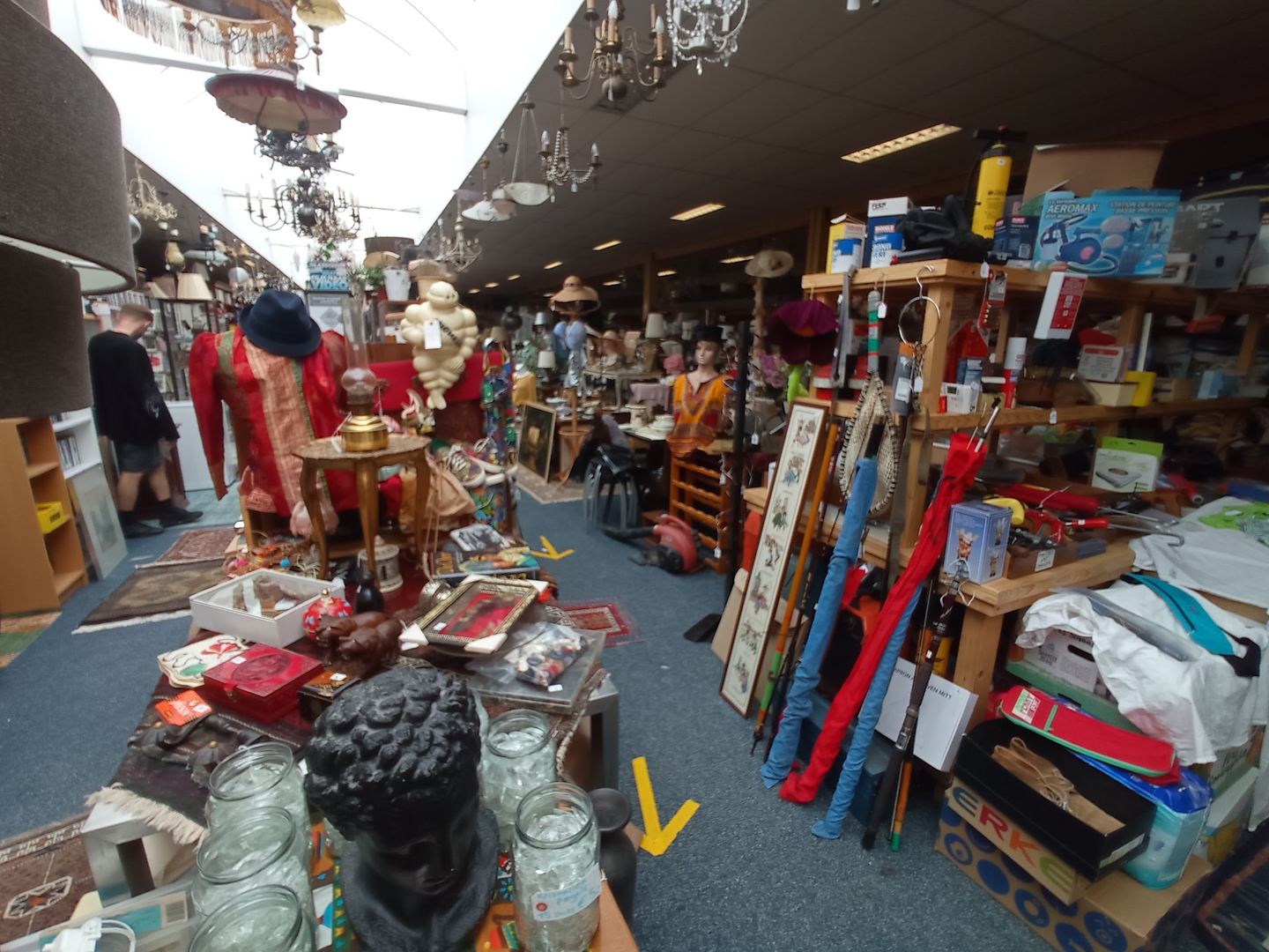 Gangpad met paspoppen, kroonluchters en rekken vol curiosa in Kringloopwinkel Rotterdam