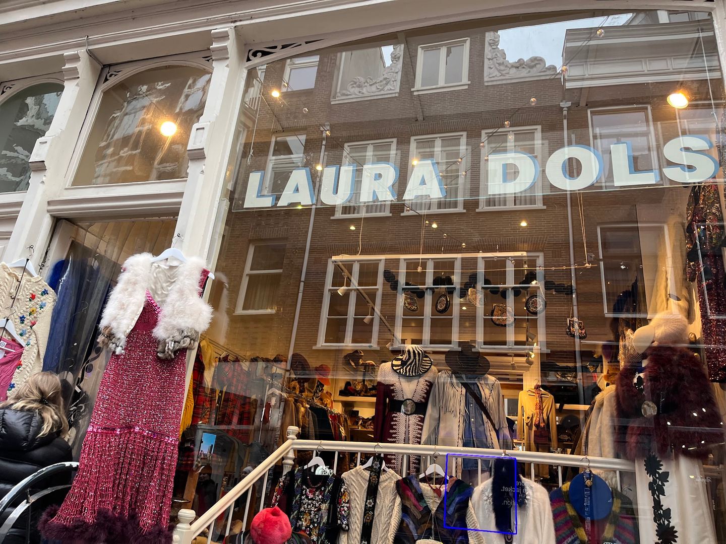 Etalage van Laura Dols met vintage jurken en de winkelnaam op het raam