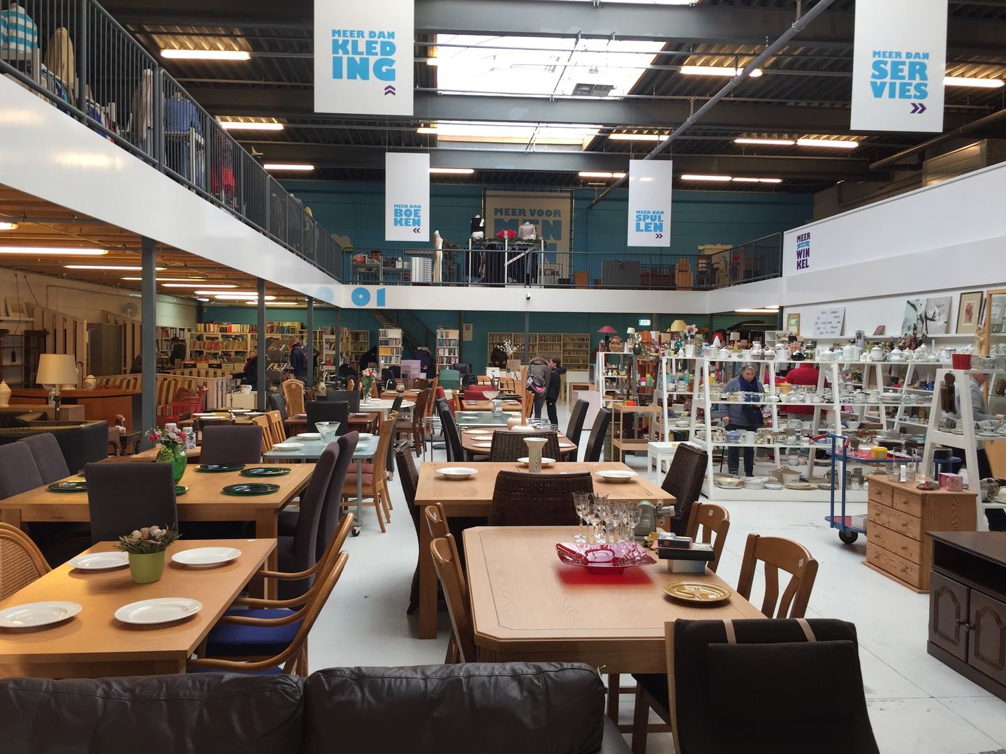 Winkelvloer van Meerwinkel met gedekte eettafels, servieskasten en een tussenverdieping met kleding