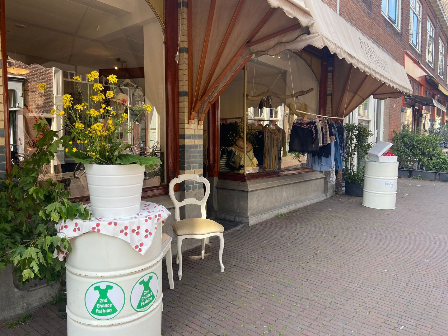 Winkelpui van MyLittleGreenDress met luifel, bloemen en kleding achter de etalage