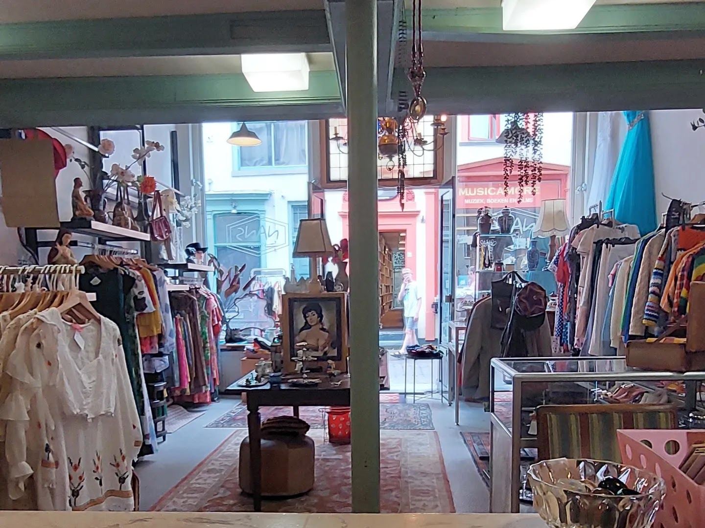 Interieur van Nans Vintage met rekken vintage kleding, vitrines en een kroonluchter