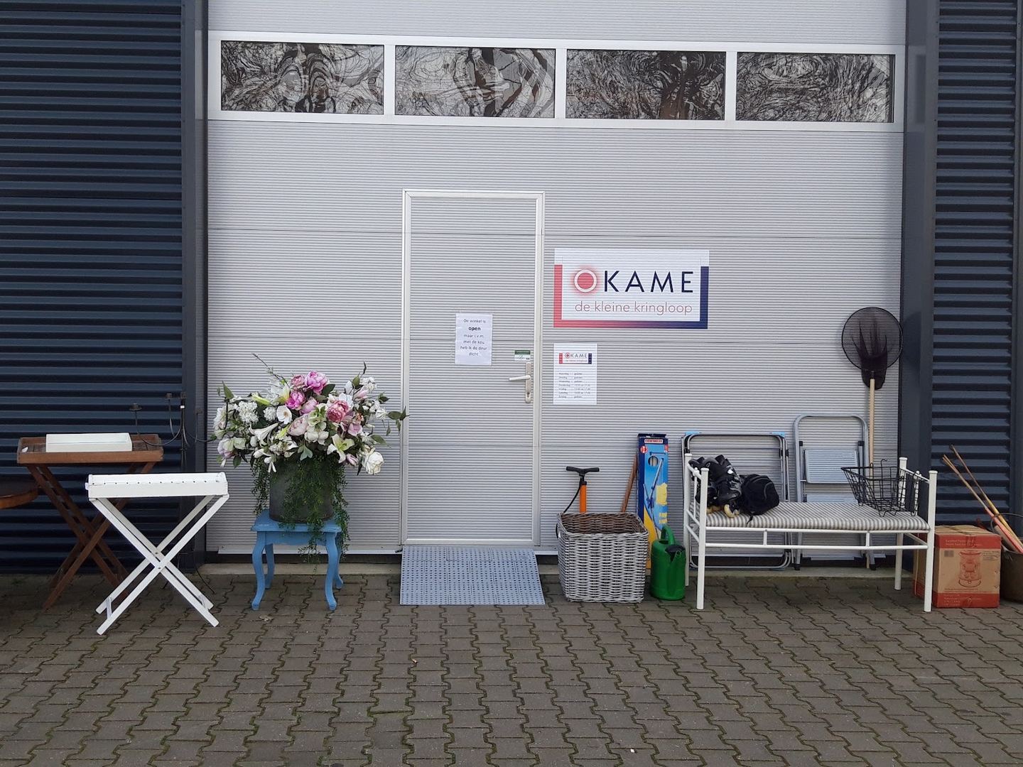 Ingang van Okame de kleine kringloop met meubeltjes en manden voor de deur