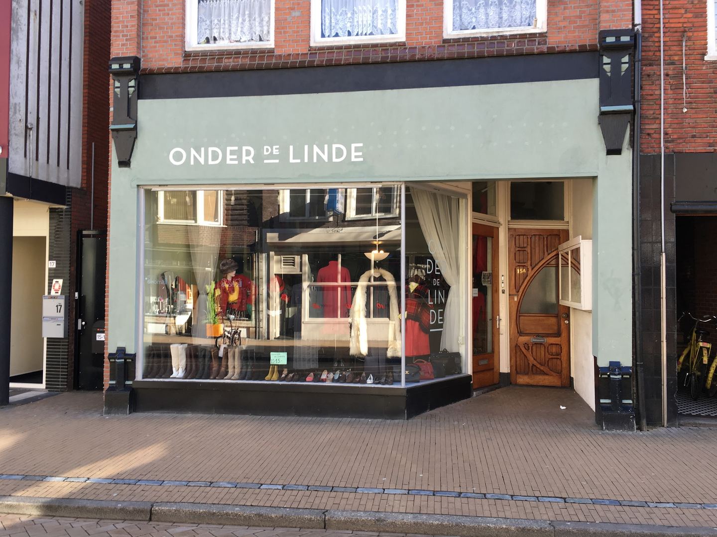Groene winkelpui van Onder de Linde met de naam boven de etalage en een houten deur