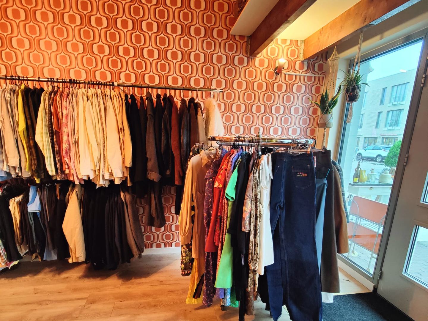 Interieur van Platform Vintage met rekken vintagekleding voor een wand met retrobehang