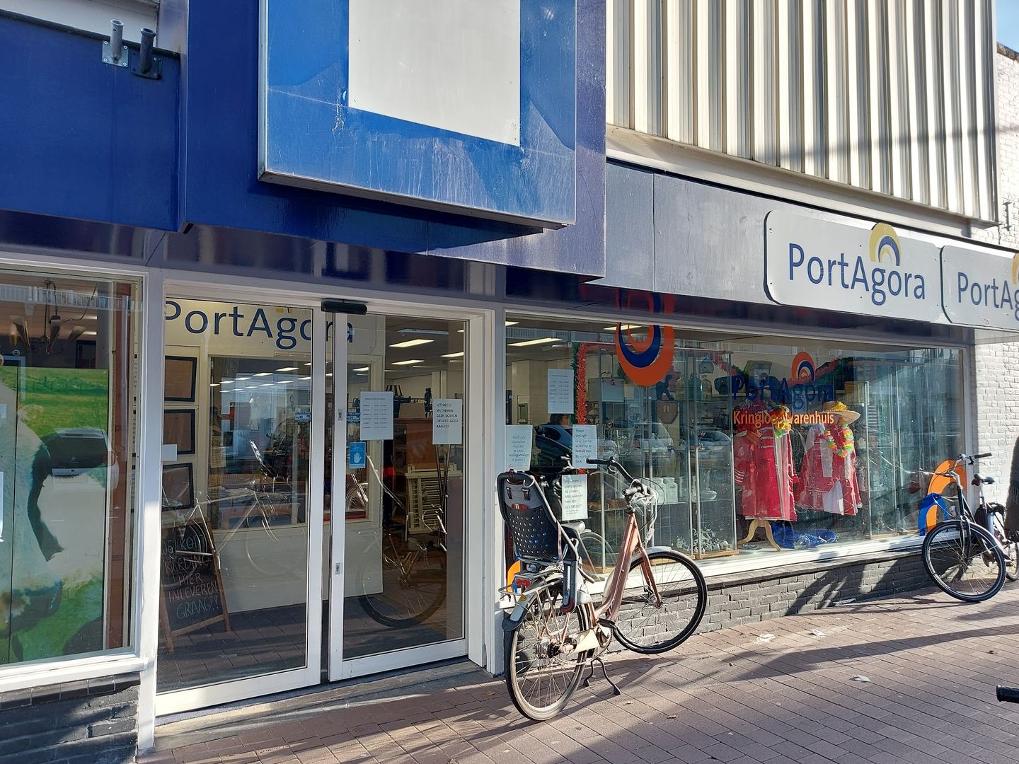 Winkelpui van PortAgora met etalage en fietsen voor de deur