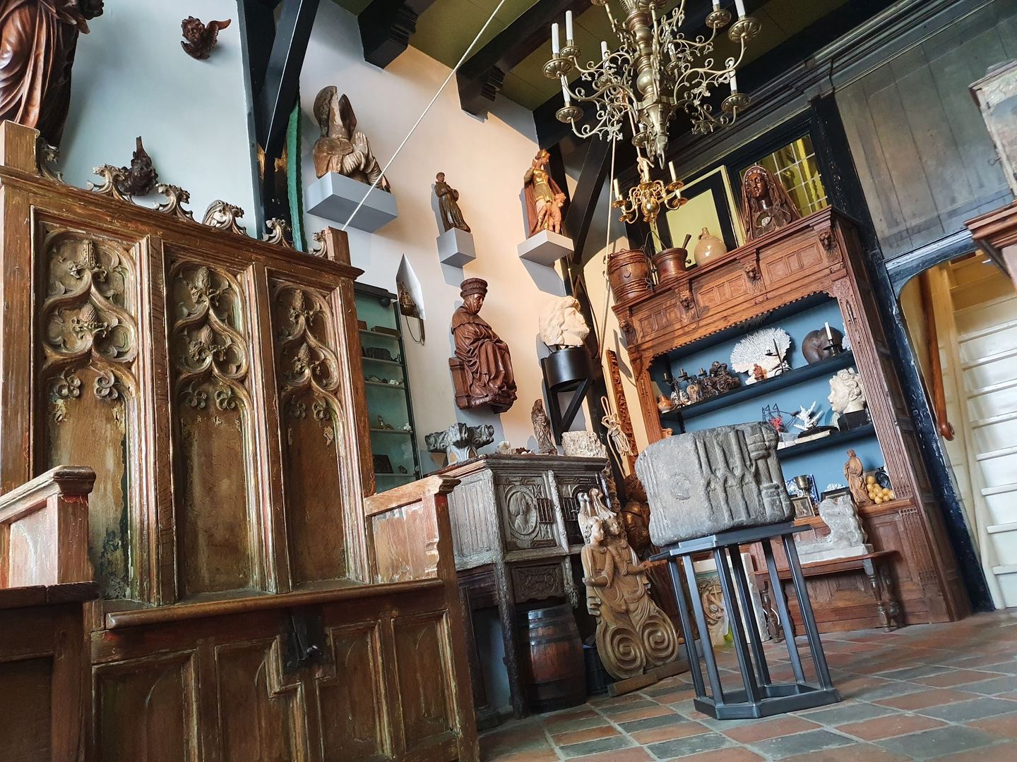 Interieur van Quellinus met gesneden eikenhouten kasten, heiligenbeelden en een kroonluchter onder houten balken